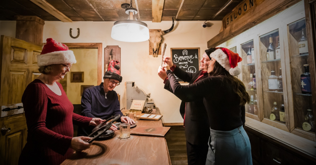Groupe d'employés en tenue festive collaborant pour résoudre des énigmes dans une salle d'évasion lors d'une activité de team building de Noël.